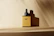 Elegant amber dropper bottle of ecoembellish hair oil surrounded by fresh rosemary and almonds on a soft beige background.
