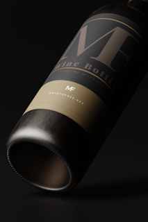 A close-up view of a wine bottle with a minimalist and elegant design. The label features large, stylized letters and subtle text beneath. The bottle is tilted on its side against a dark background, emphasizing the sleek and polished appearance.