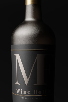 A close-up view of an elegantly designed wine bottle with a matte black label and bold silver markings. The bottle appears metallic, with a sleek, sophisticated look.