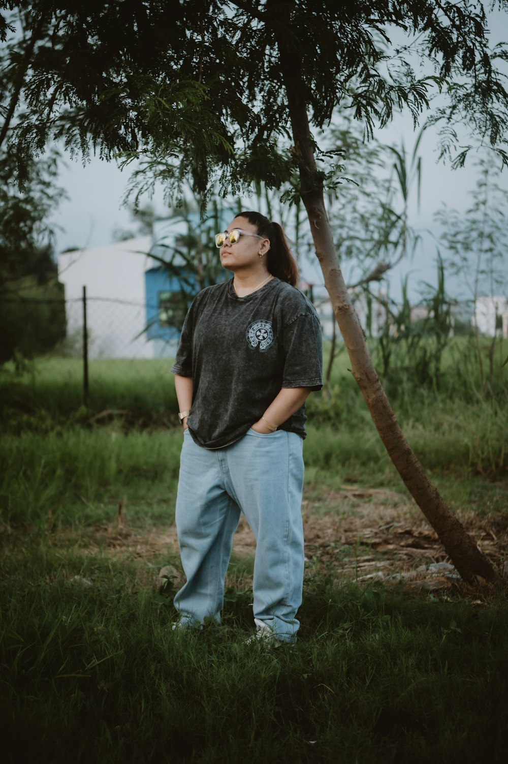 a man standing next to a tree in a field