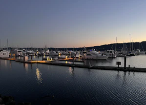 A serene marina at sunset with boats gently rocking by the docks.