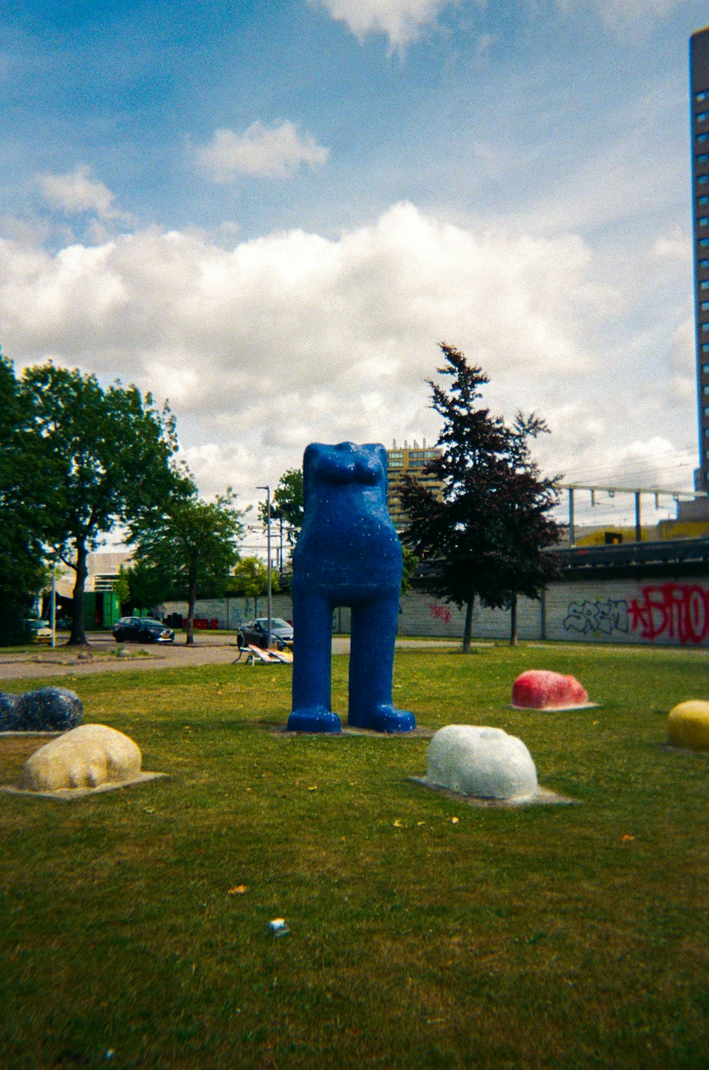 a blue bear statue sitting in the middle of a field