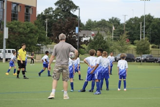 An enthusiastic coach giving instructions to young soccer players on the field.