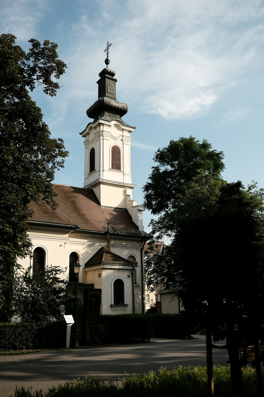 une église avec un clocher entouré d’arbres