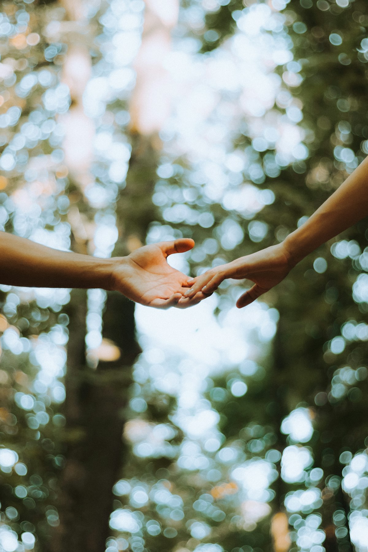 Two people reaching out, hands almost touching but not yet