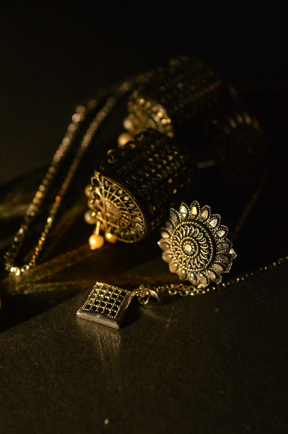 a black table with a gold necklace and a cell phone on it