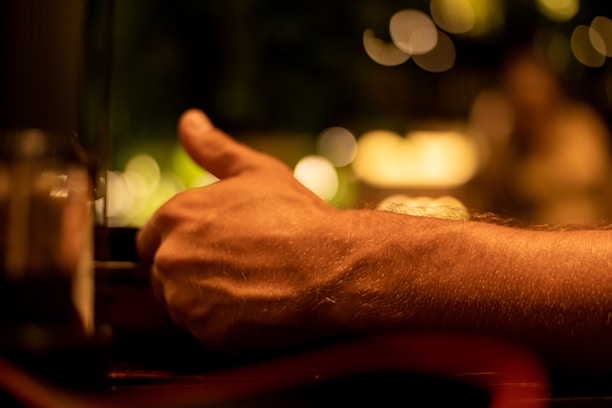 Close-up of a satisfied customer giving a thumbs-up in a cozy restaurant setting.