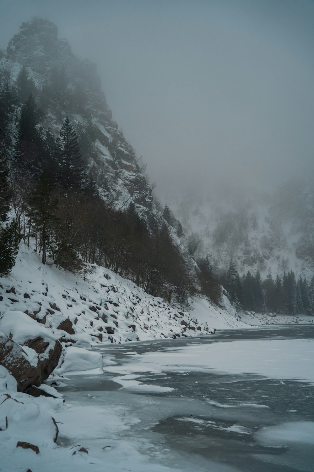 a frozen lake surrounded by snow covered mountains