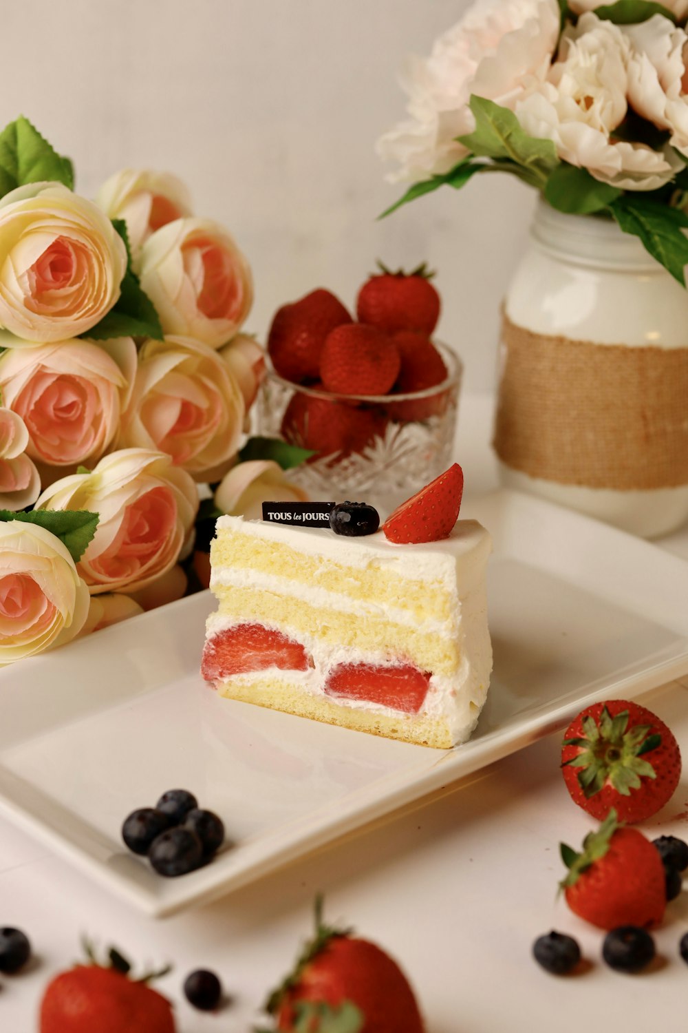 a piece of cake on a plate with strawberries and blueberries