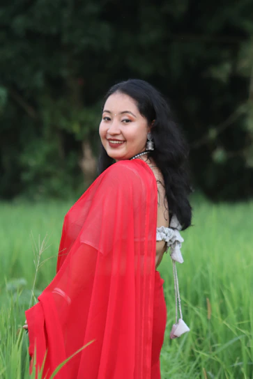 Portrait of Dilruba Khanam in a deep forest green saree, standing in a lush agricultural field.