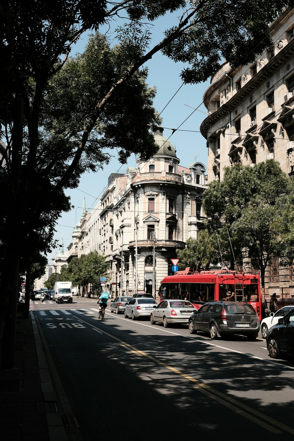 a red bus driving down a street next to tall buildings