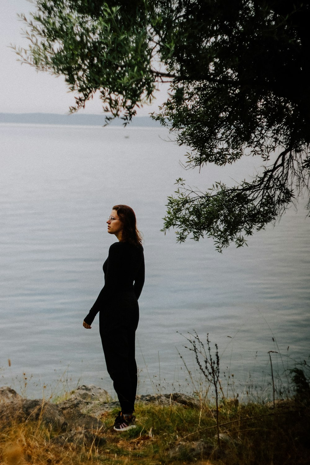 a woman standing on the shore of a lake