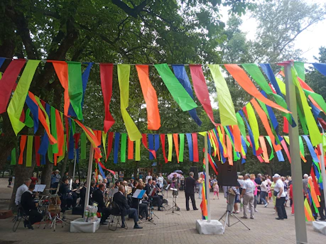 Neighbors gathered in a park sharing food and stories under colorful banners promoting peace.