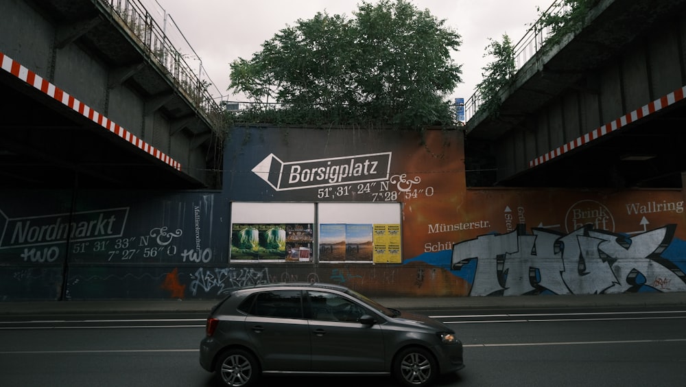 Ein Auto, das neben einer mit Graffiti bedeckten Wand eine Straße entlang fährt