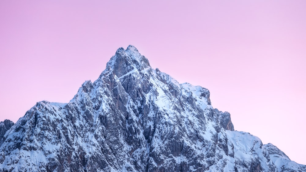 Una montaña cubierta de nieve con un cielo rosado en el fondo