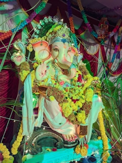 A vibrant and elaborately decorated statue of Lord Ganesha, adorned with flowers and traditional decorations, surrounded by colorful fabrics and festive lights.