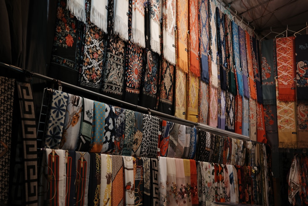 a wall full of different colored scarves