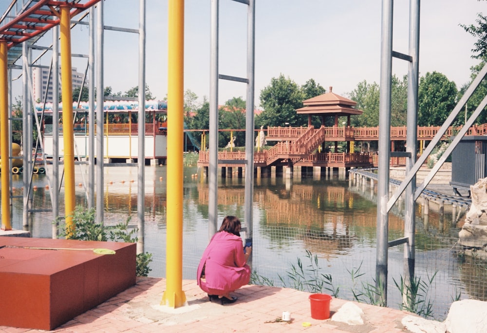 a woman sitting on the ground next to a body of water