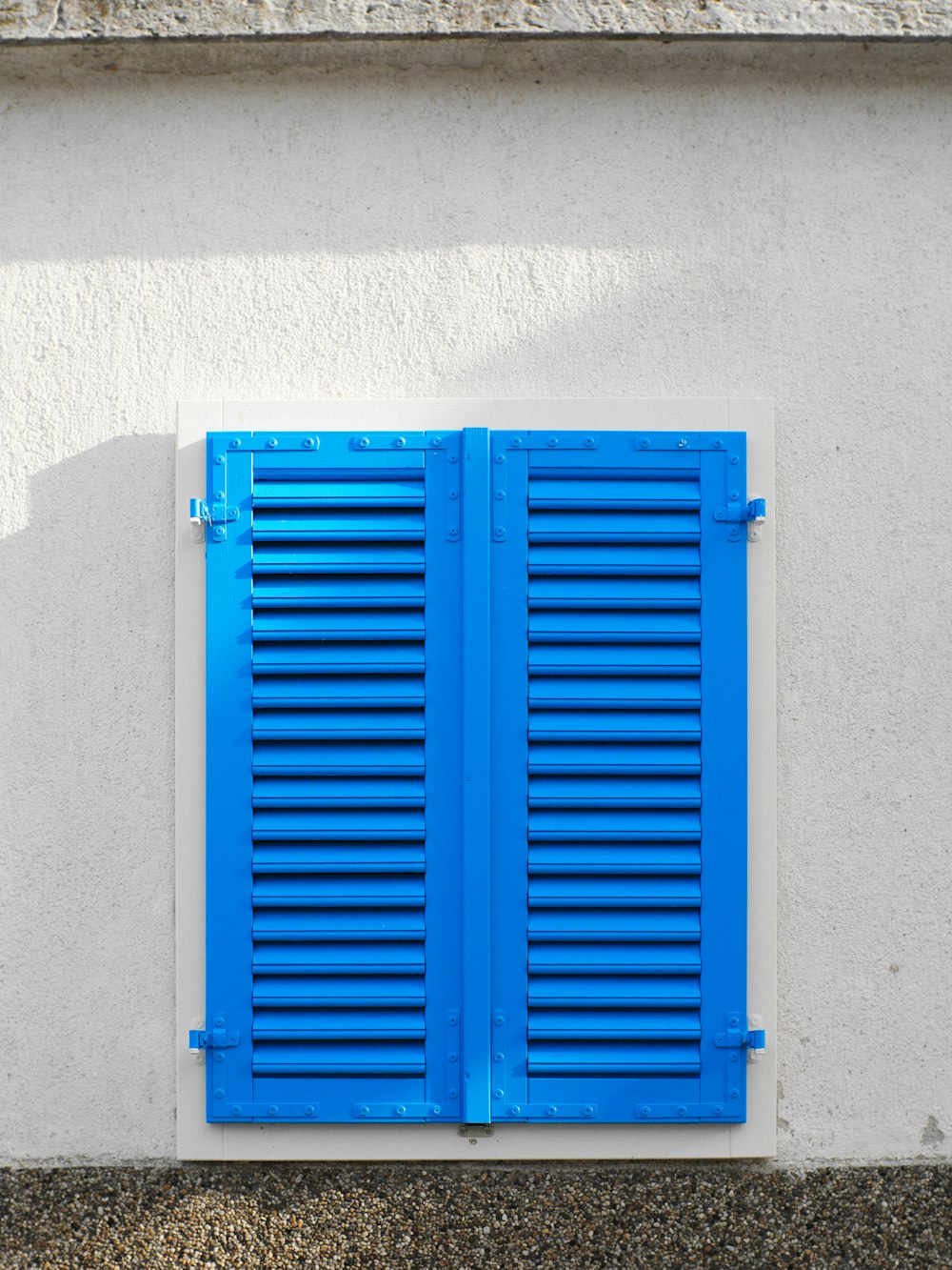 a blue shuttered window on a white wall