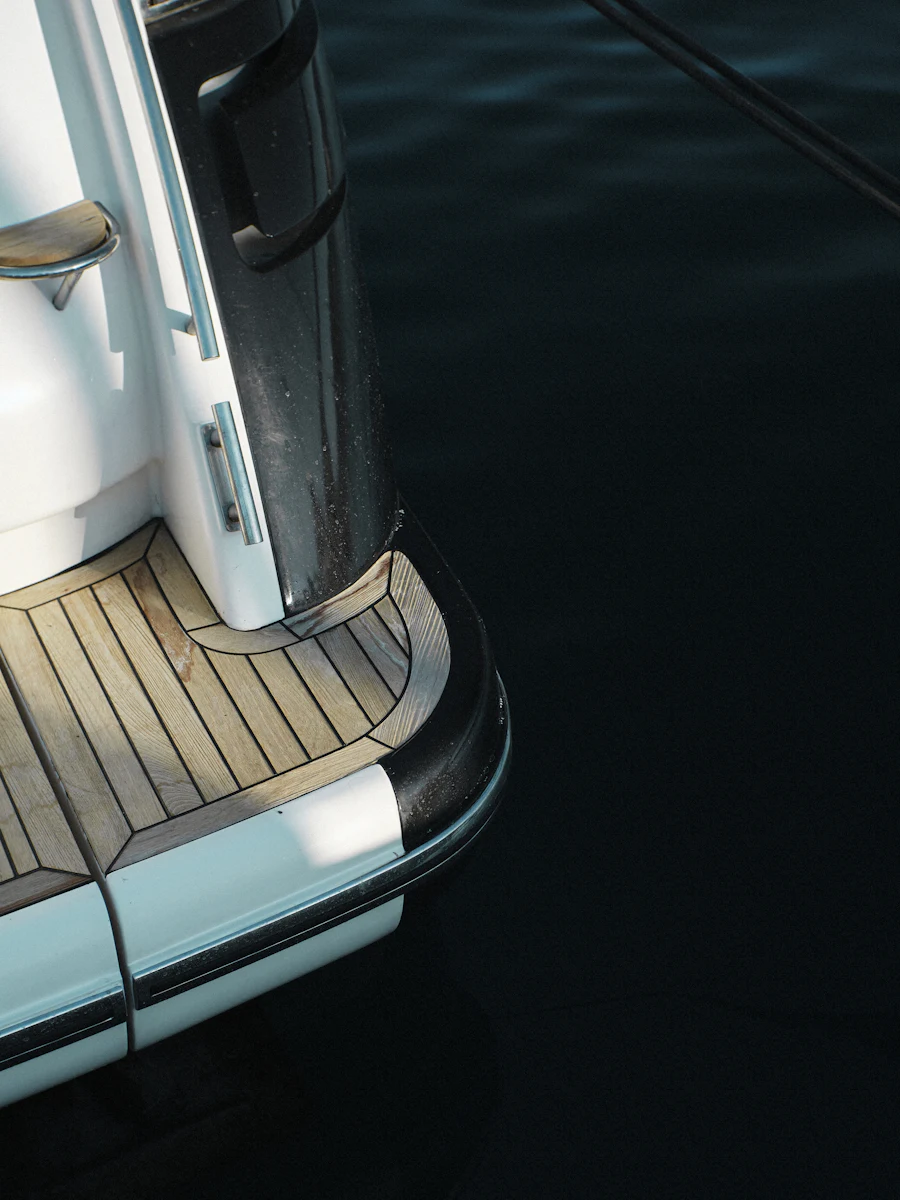 The curve of a yacht hull meeting a teak deck, close.