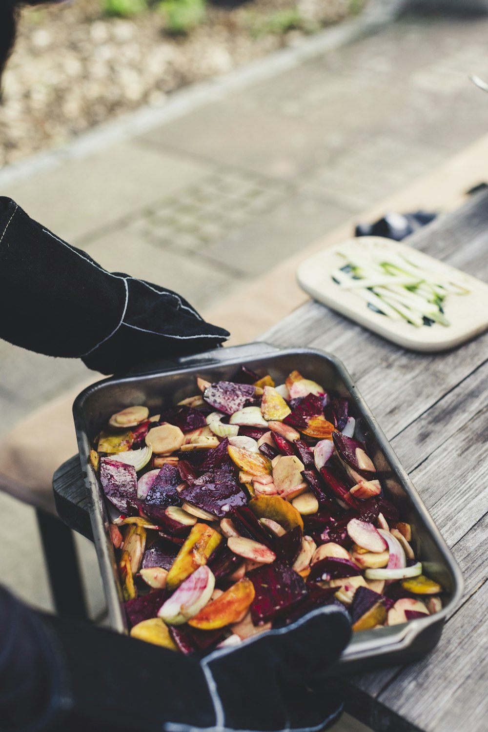 a person holding a pan of food on a picnic table