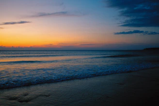 A serene beach at sunset with gentle waves and a colorful sky.