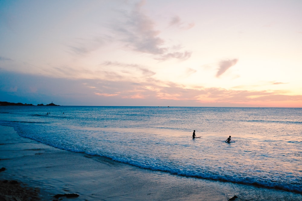 a couple of people in the water at the beach