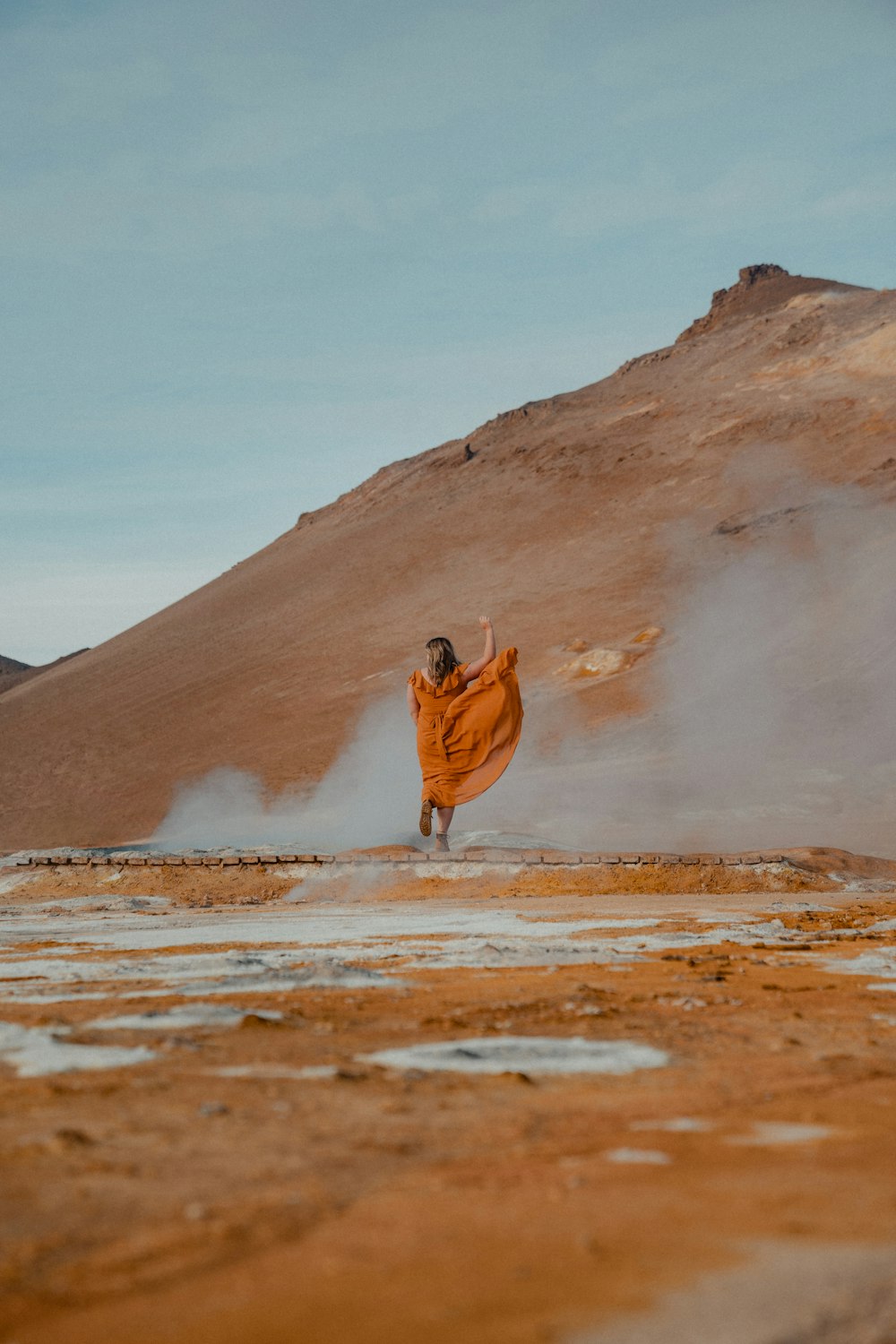 Una mujer con un vestido naranja corre por el desierto