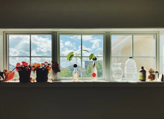 Bright window sill lined with mason jars filled with fresh wildflowers and herbs.