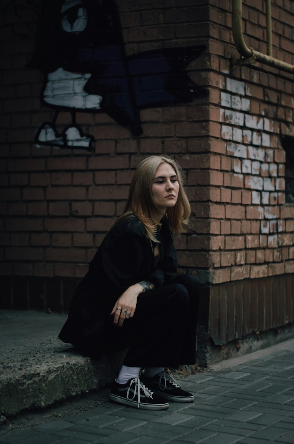 a woman sitting on the side of a brick building