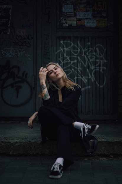 a woman sitting on the ground in front of a building Agencia La Movida Creación de contenido