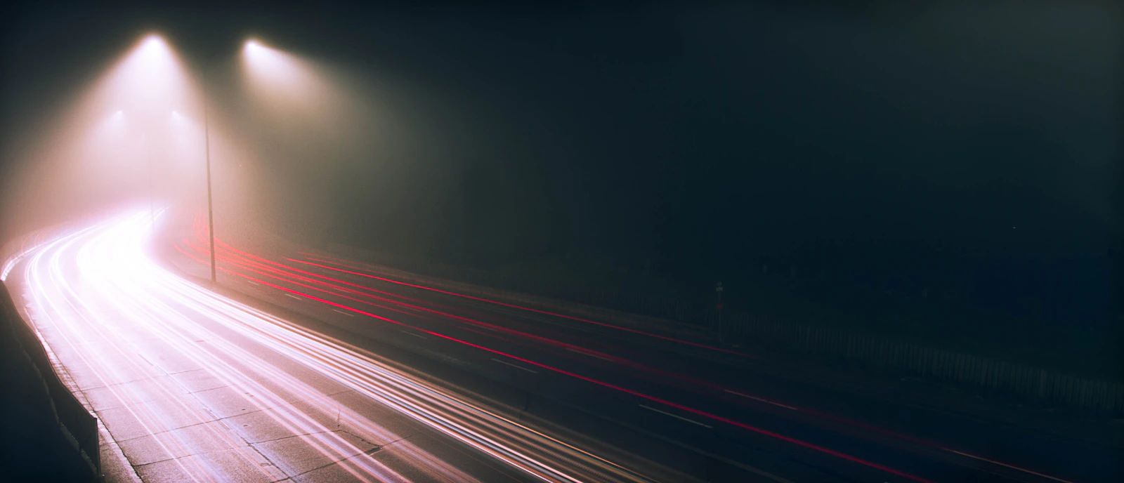 Long exposure of traffic light trails on a foggy highway at night