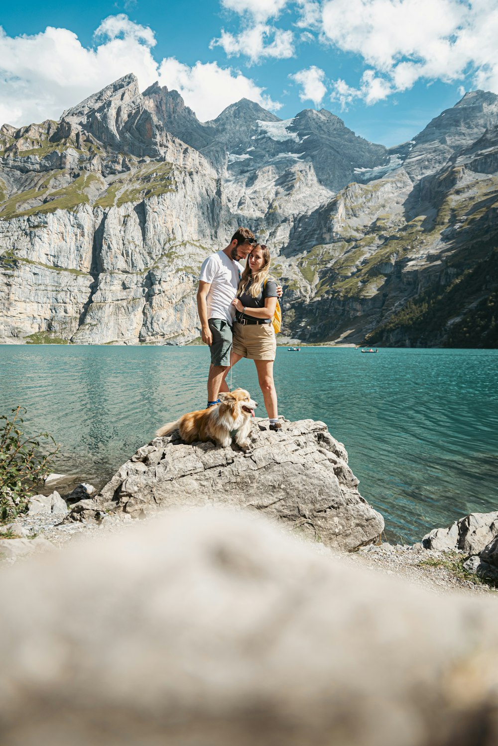 a man and woman standing on a rock next to a dog
