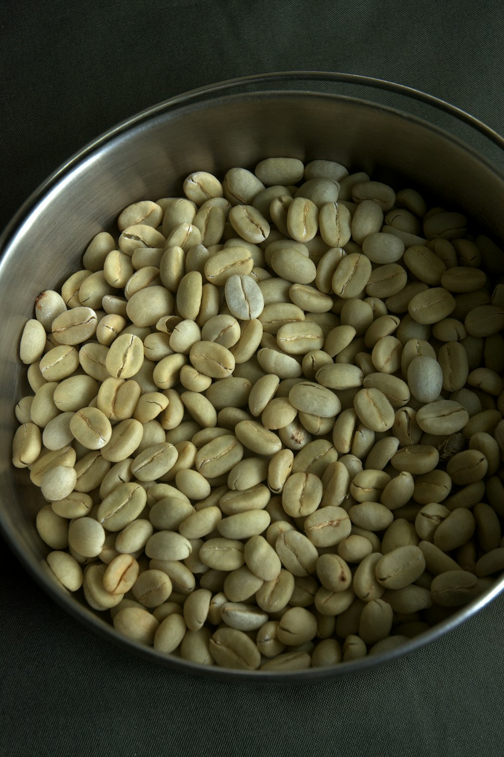 a metal bowl filled with beans on top of a table