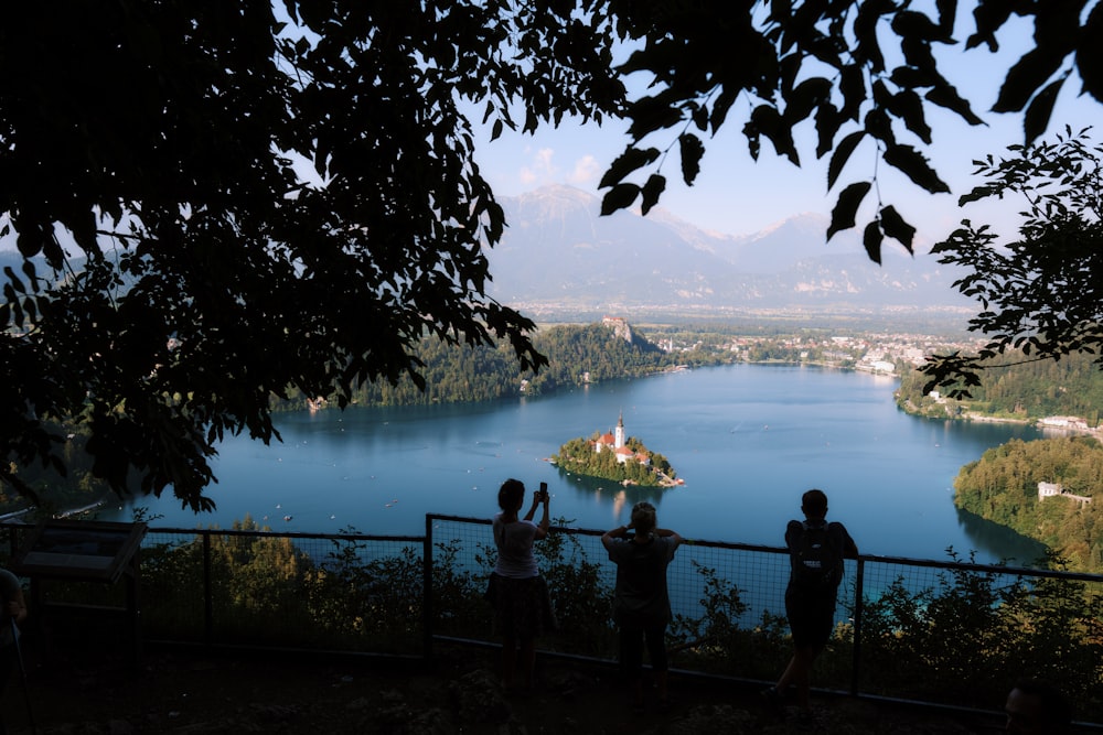 a group of people standing on top of a hill next to a lake