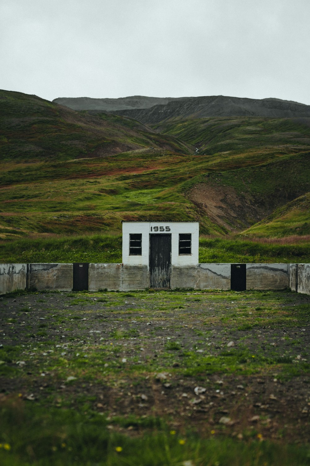 a small white building sitting on top of a lush green hillside