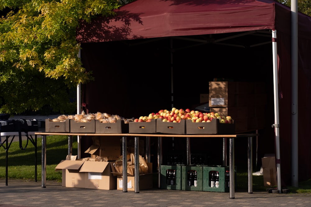 an outdoor fruit stand with boxes of apples