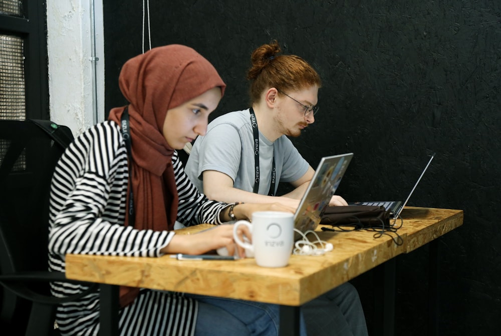 two women sitting at a table with laptops