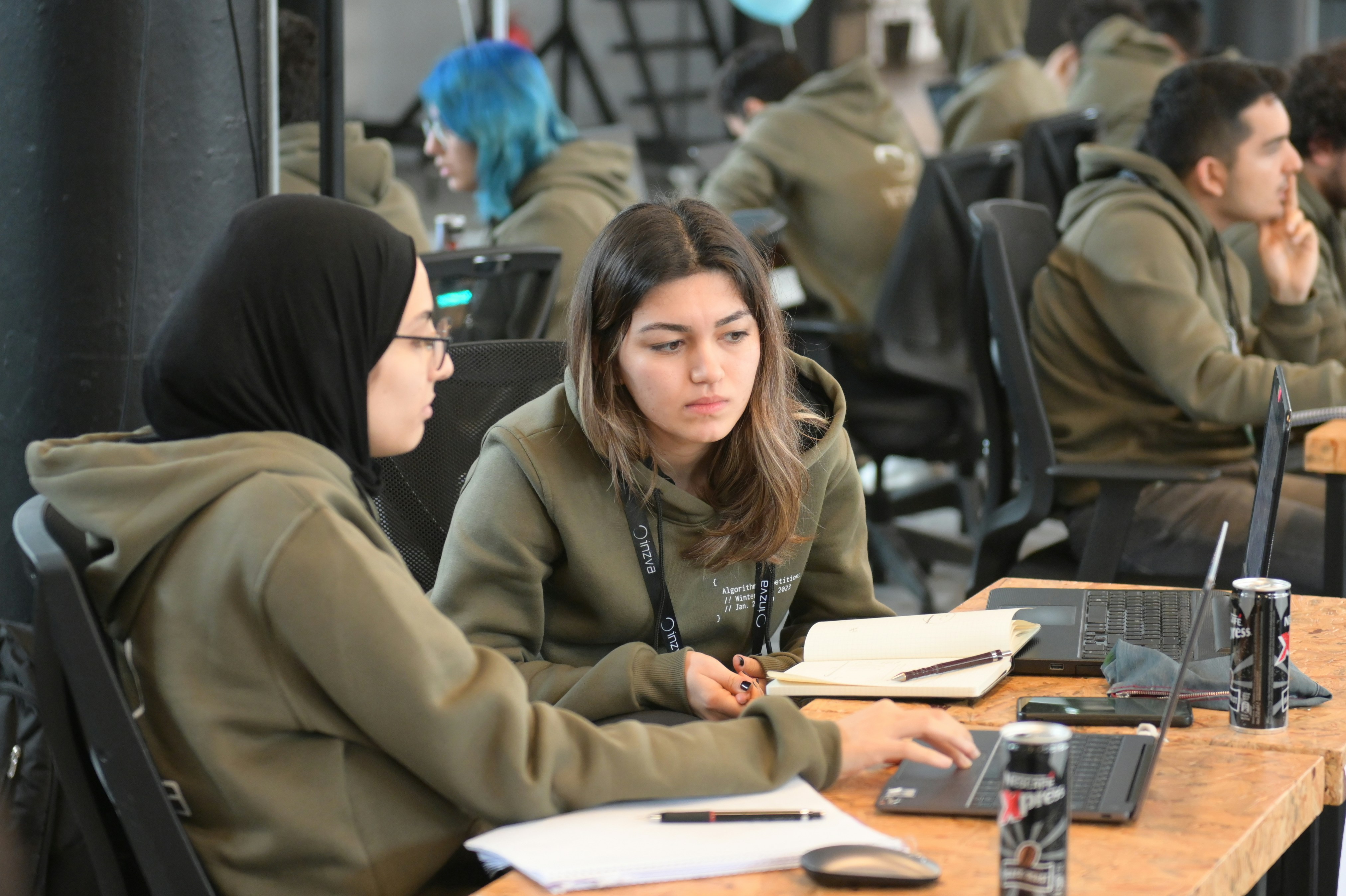 a group of people sitting at a table with laptops