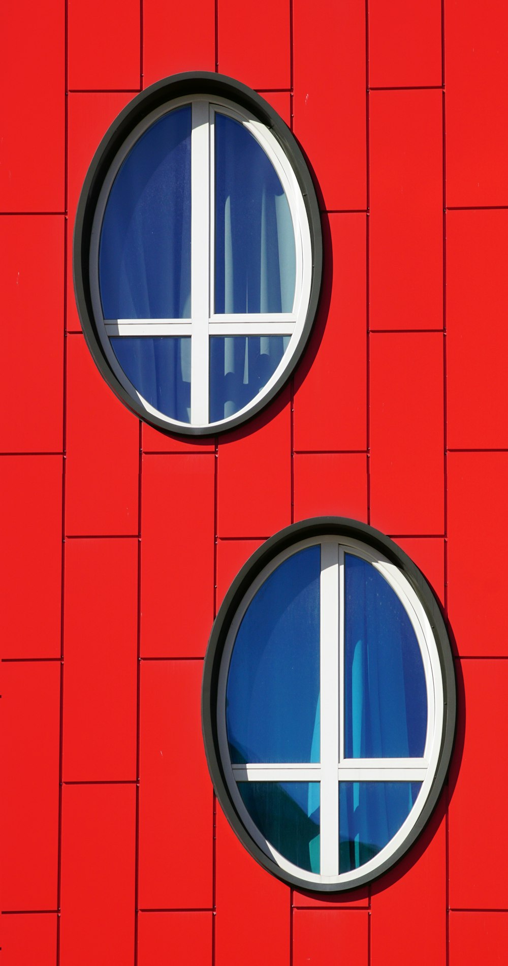 two round windows on the side of a red building