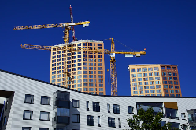 A bright, modern construction site with cranes and green trees, symbolizing sustainable building.