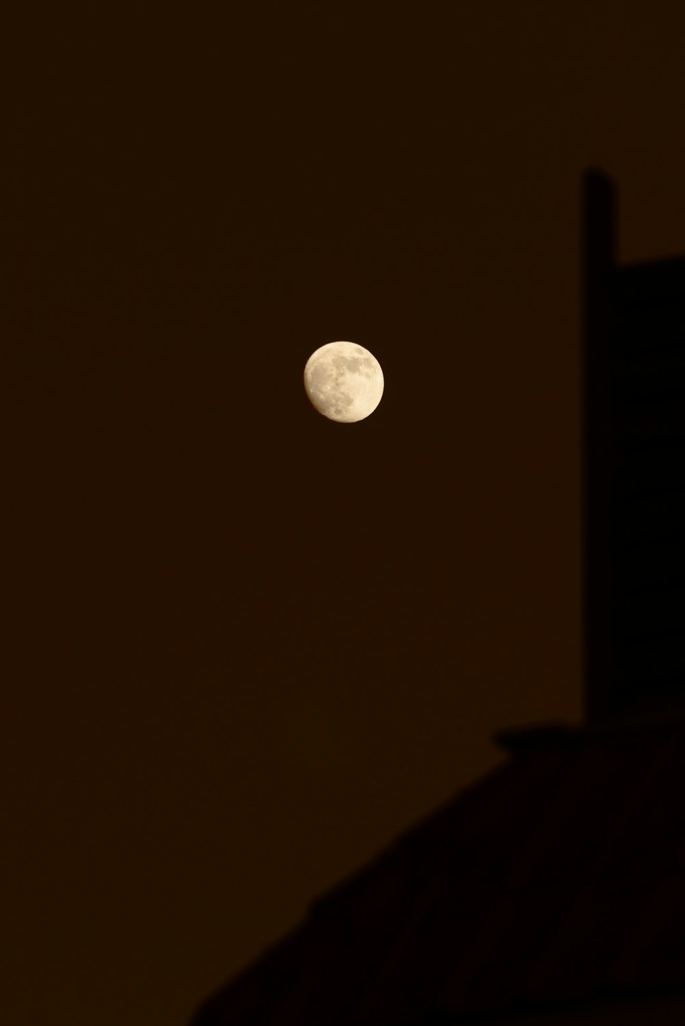 a full moon is seen in the sky above a building