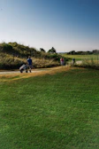 A scenic view of a clubhouse with women golfers walking towards it after a game.