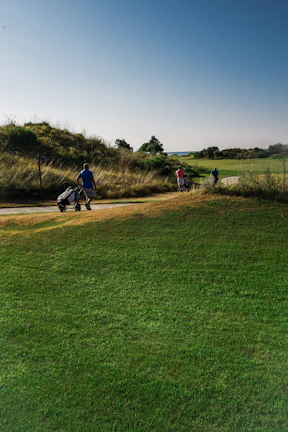 A scenic view of a clubhouse with women golfers walking towards it after a game.