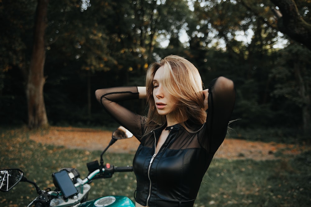 a woman in a black leather outfit standing next to a motorcycle