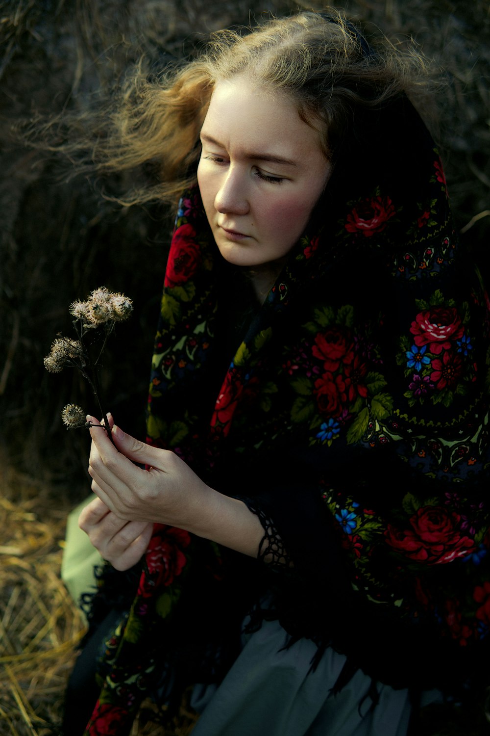 a woman sitting on the ground holding a flower