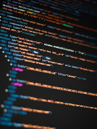 Colorful lines of HTML and JavaScript code are displayed on a computer screen, highlighted in different colors to differentiate elements, attributes, and text.