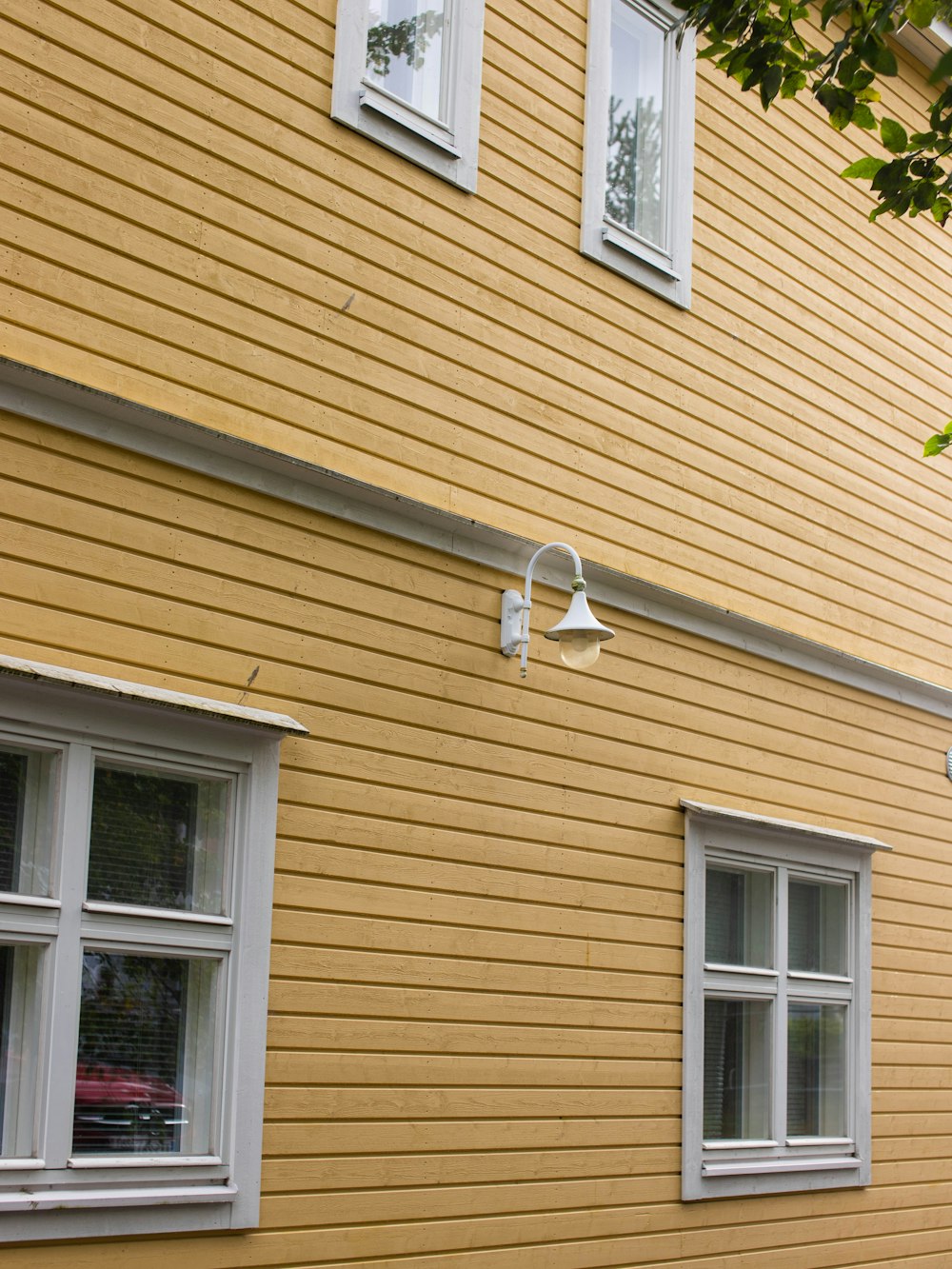 a yellow building with two windows and a street sign