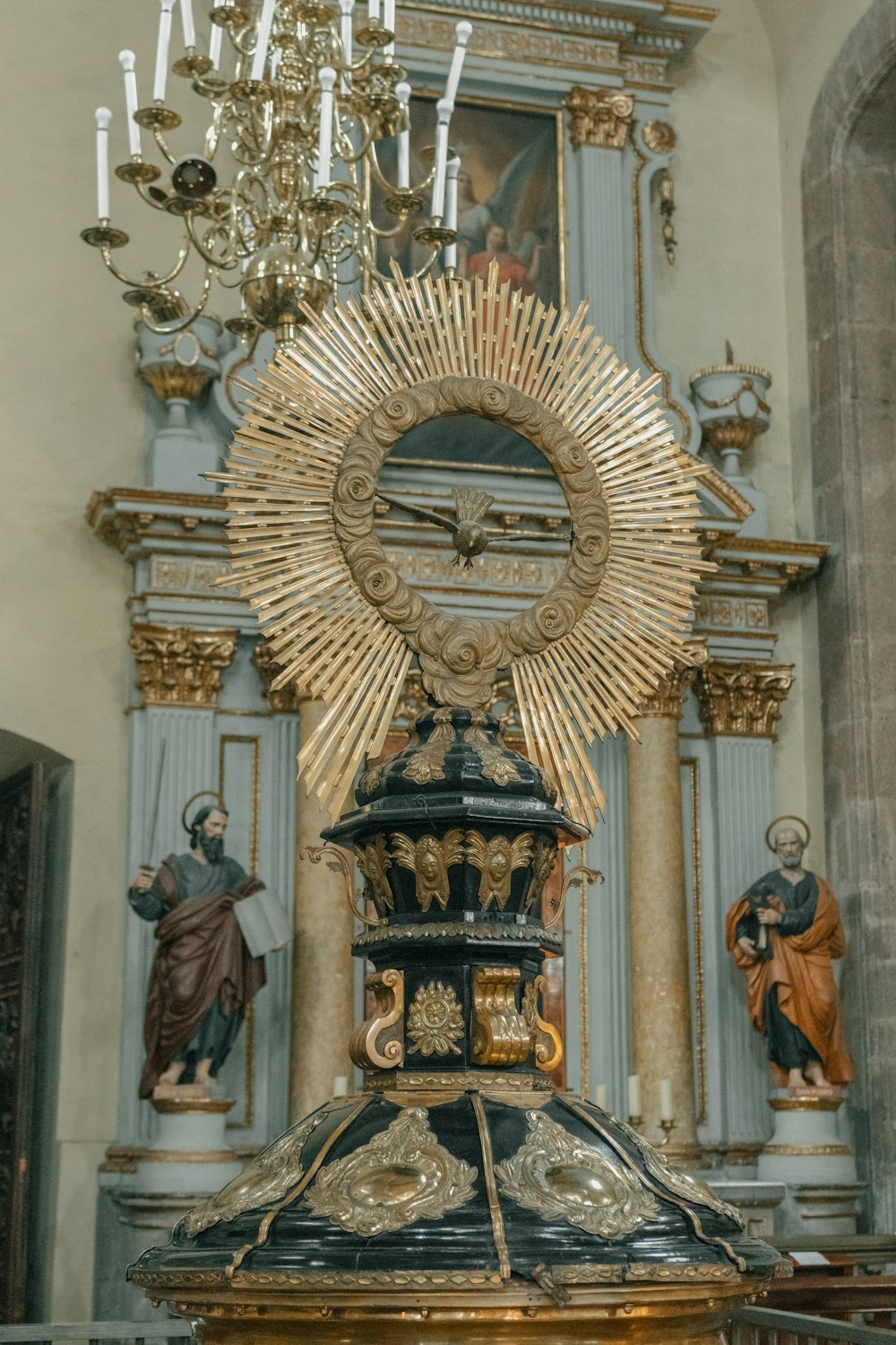 a statue of a cross in front of a chandelier