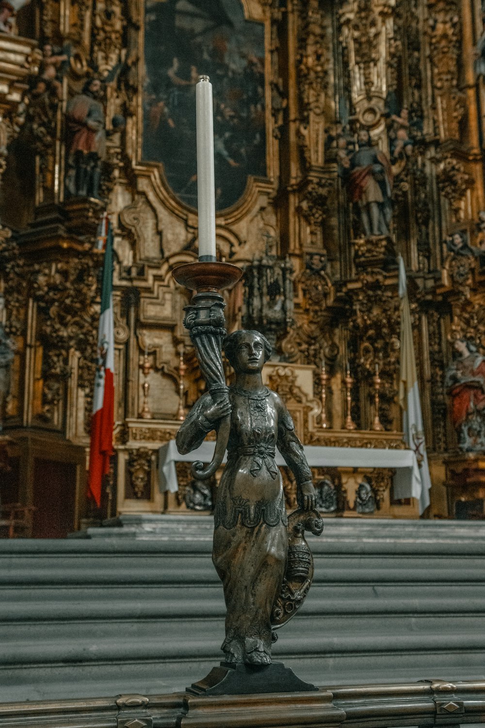 eine Statue einer Frau, die eine Kerze vor einer Kirche hält